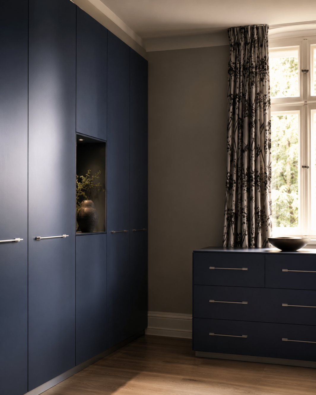 Deep blue custom wardrobe wall with lit display niche and matching dresser